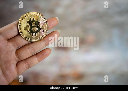 Close up one golden coin with the bitcoin symbol in hand. Young hand holding cryptocurrency coin, Money coins digital, BTC. Stock Photo