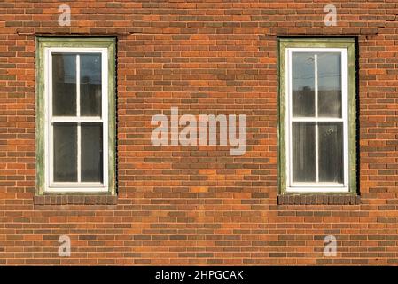 Red brick wall with two windows. Stock Photo