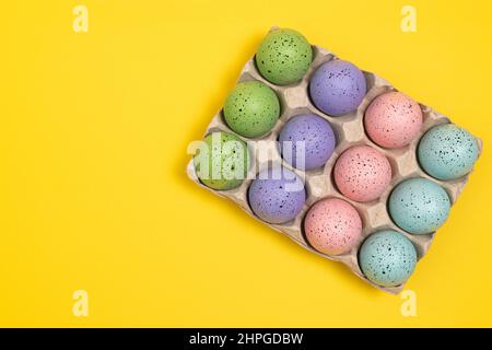 Colorful Easter eggs in egg carton. Flat lay Easter Celebration background with copy space Stock Photo