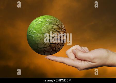 finmger holding a earth globe partially dried, global warming concept Stock Photo