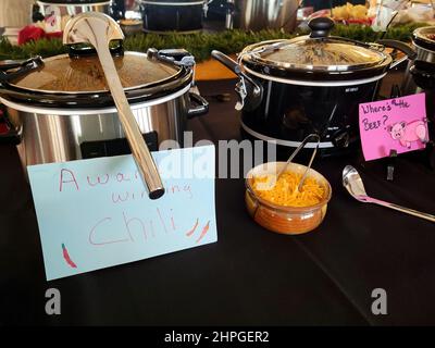 A row of crockpots on a tablecloth in a chili cook-off contest Stock Photo