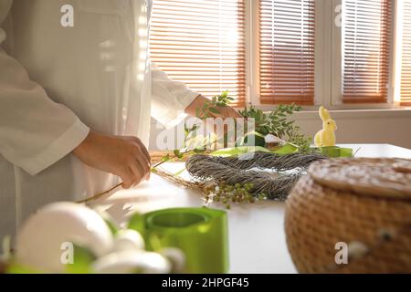 Woman making beautiful Easter wreath at table, closeup Stock Photo