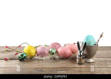 Painted Easter eggs and figurine of bunny on table against white background Stock Photo