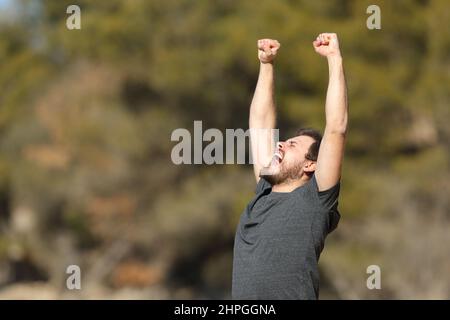 Excited man raising arms celebrating good day in nature Stock Photo