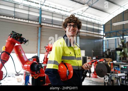 engineer checking control panel and teaching new Automatics robot arm and operating control machine in factory. Stock Photo