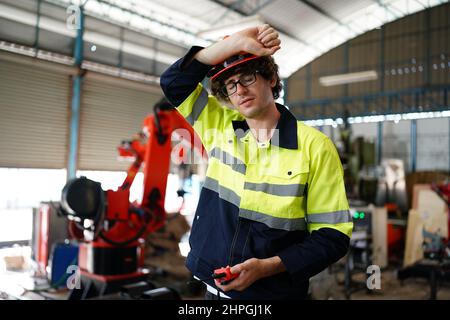 engineer checking control panel and teaching new Automatics robot arm and operating control machine in factory. Stock Photo