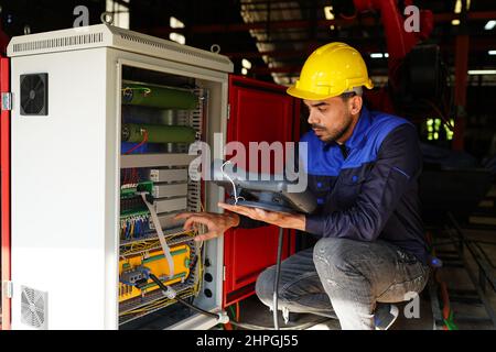 engineer checking control panel and teaching new Automatics robot arm and operating control machine in factory. Stock Photo