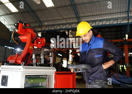 engineer checking control panel and teaching new Automatics robot arm and operating control machine in factory. Stock Photo
