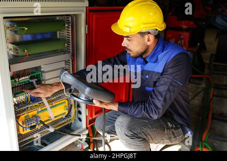 engineer checking control panel and teaching new Automatics robot arm and operating control machine in factory. Stock Photo