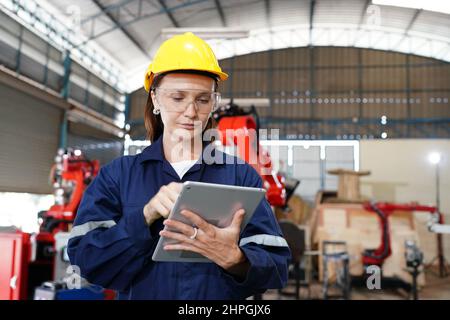 Professional young industrial factory woman employee working with machine parts putting, checking and testing industrial equipments and robot arms in Stock Photo