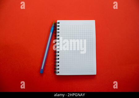 Blank open notebook and pen isolated on red background. Top view, flat lay. Stock Photo