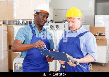 Professional male contractors discussing while determining scope of building work indoors. Stock Photo