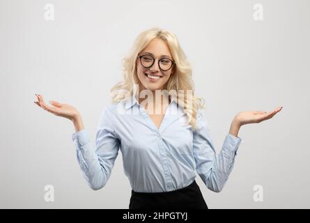 Positive woman in formal wear comparing options, making scales with her hands, holding invisible objects Stock Photo