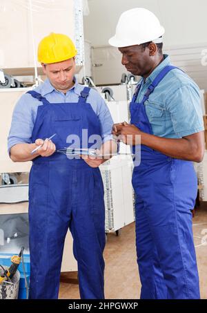 Professional male contractors discussing while determining scope of building work indoors. Stock Photo