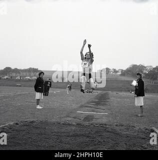 1960s, historical, an adult female athlete in mid-air doing the long jump, Fife, Scotland, UK. Speed, strength and agility - and determination -  are all needed in this great track and field event, where the goal is to leap as far as possible into a sandpit from a takeoff point on the run-up. A men's event in the original modern Olympics of 1896, women first took part in the Olympic long jump in 1948 in London. Stock Photo