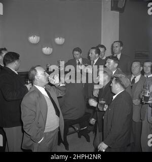 1950s, historical, a group of steel workers in the company social club after work, having a drink together and a sing song, at a piano, Port Talbot, Wales, UK. Stock Photo