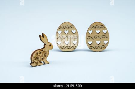 Easter decor on a light background. Decorations for the feast of Holy Easter. Wooden figurines of eggs and a rabbit for Easter. Stock Photo