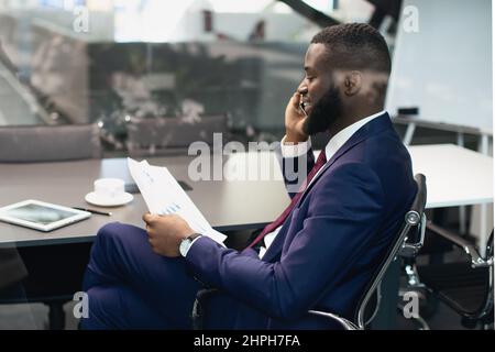 African american manager having phone conversation, reading papers Stock Photo