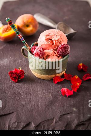 Italian style ice cream (gelato) in a cup with fruit on a slate background. Sweet and summer menu concept. Stock Photo
