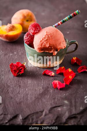 Italian style ice cream (gelato) in a cup with fruit on a slate background. Sweet and summer menu concept. Stock Photo