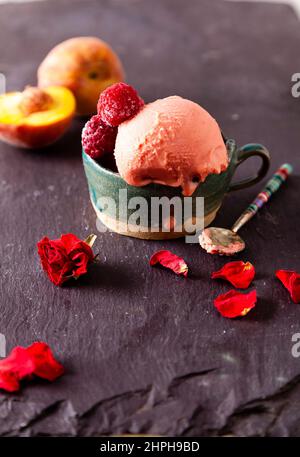 Italian style ice cream (gelato) in a cup with fruit on a slate background. Sweet and summer menu concept. Stock Photo