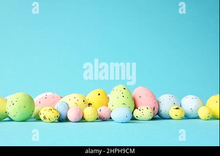 Row of painted colored easter eggs on blue background. Happy Easter background. Stock Photo