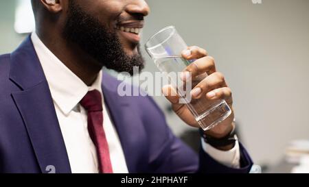 Unrecognizable bearded black man in suit drinking water Stock Photo