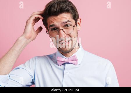Young white man scratching his head and looking at camera isolated over pink background Stock Photo