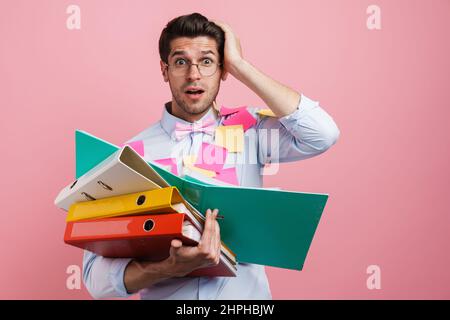 Young white shocked man with stickers posing with document cases isolated over pink background Stock Photo