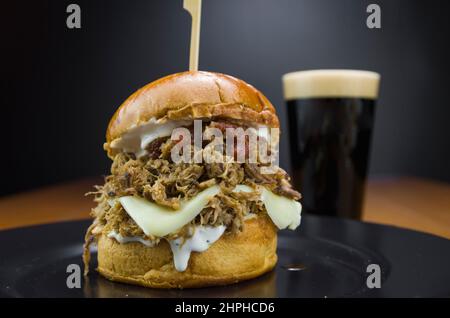 Close-up of tasty homemade pulled pork burger on wooden table and black background Stock Photo