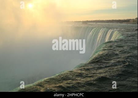 Canadian side of Niagara Falls at Sunrise in February 2022, with a mist rising above water. Stock Photo
