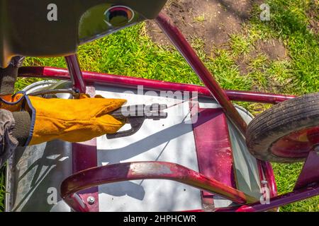 The man works by welding. A welder repairs an iron garden cart using electric welding. Stock Photo