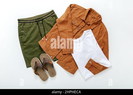 Set of stylish clothes flip flop Slates T-shirt shorts denim jacket On white background top view. Men's summer clothes casual outfits. Fashionable Stock Photo