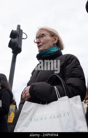 Mature female waits to cross the road carrying a Laura Ashley bag, London UK Stock Photo