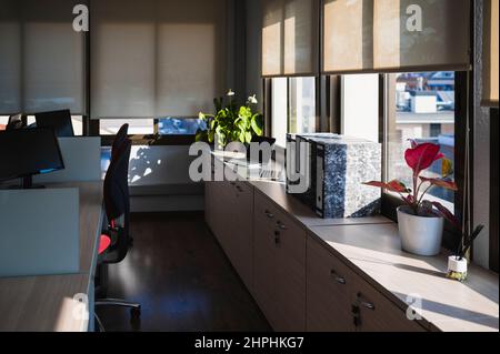 Empty office illuminated by natural light with several work desks. Stock Photo
