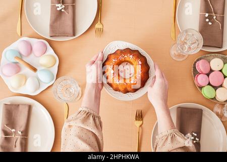 Top view close up of young woman putting food on dinner table decorated for Easter and Spring, copy space Stock Photo