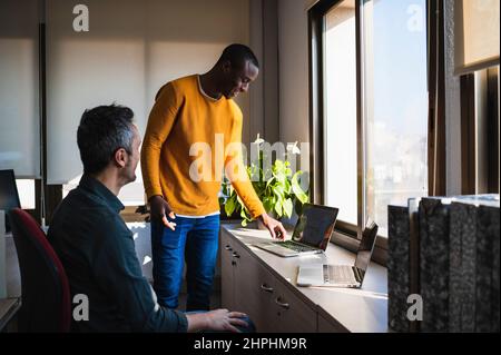 Two men relaxed working in an office with laptop. Stock Photo