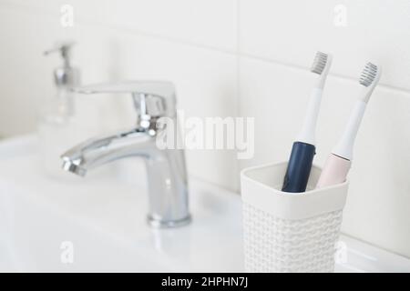 New modern ultrasonic toothbrushes in a glass on the bathroom sink. Jaw model and dental care supplies. Oral hygiene, dental and gum health, healthy Stock Photo