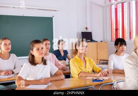 Students writing in notepads during lesson Stock Photo