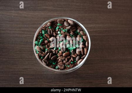 Centerpiece of coffee beans into a white cup over wood table. Brown background. Stock Photo