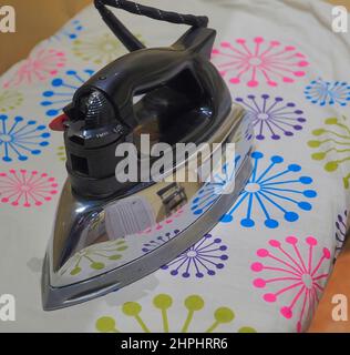 Vintage iron on colorful ironing board Stock Photo