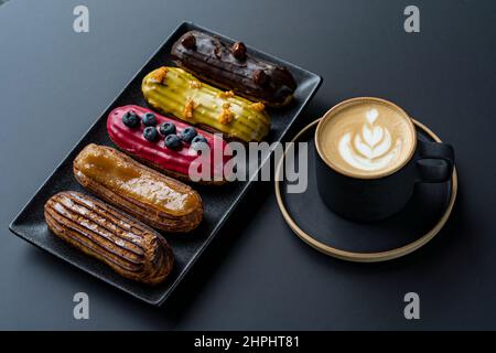 Delicious eclairs, on a dark plate on a dark background. Space for copying. Sweets Stock Photo