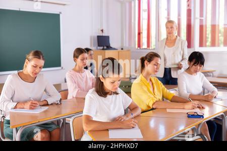 Students writing in notepads during lesson Stock Photo