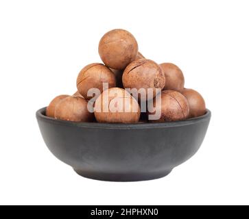 Heap of macadamia nuts in dark bowl isolated on white background Stock Photo