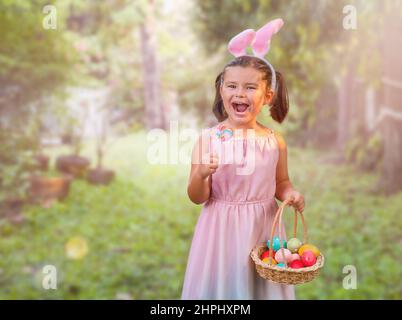 Child girl with basket and easter eggs in the backyard Stock Photo