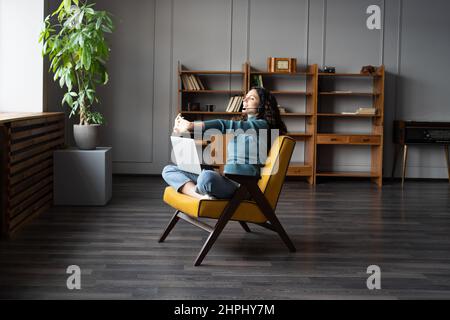 Young relaxed woman doing hand exercises at remote workplace, working during COVID-19 lockdown Stock Photo