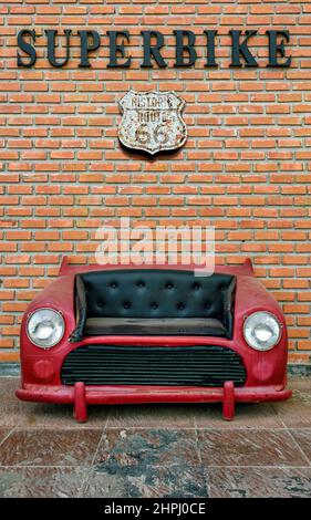 A red car sofa with black faux upholstery, on isolated background with clipping path. Stock Photo