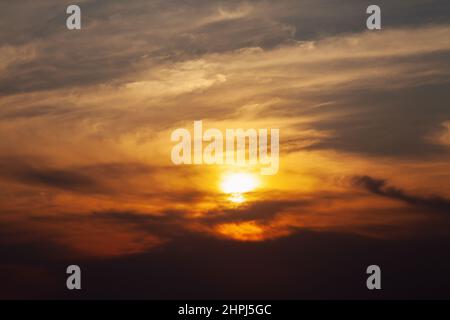Sun behind the clouds at sunset Stock Photo