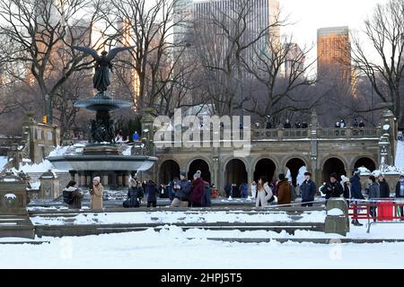 Tourists at a snow covered Bethesda Fountain and terrace in the winter taken from a frozen lake in Central Park, New York, NY. Stock Photo