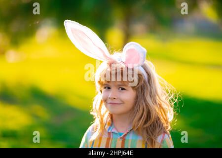 Bunny child boy face. Easter bunny children. Kids boy in bunny ears in park outdoor. Stock Photo